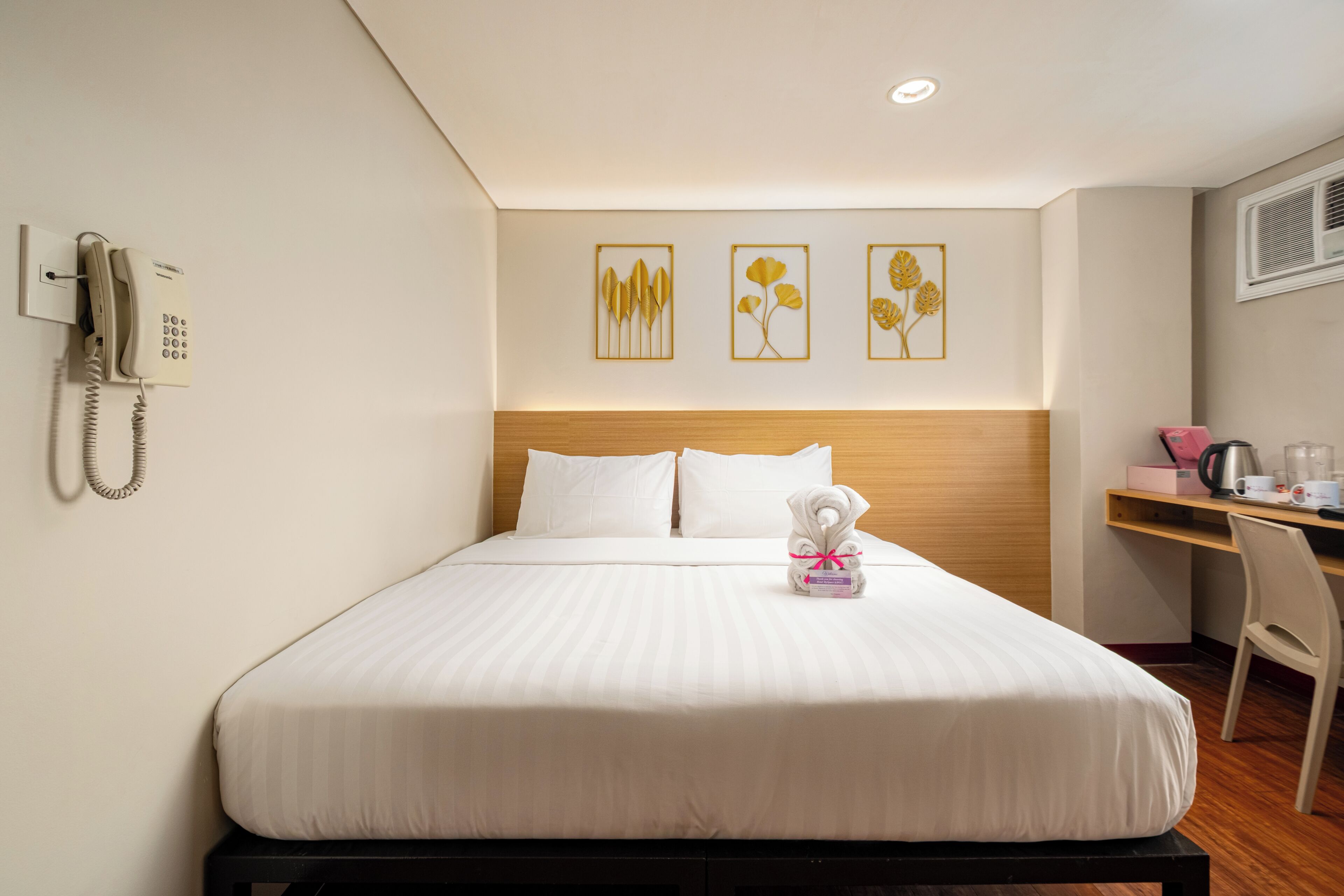 A hotel room with a bed, a desk, a telephone, and wall art.