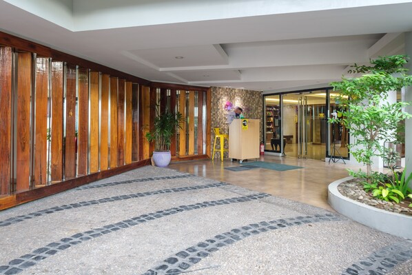 A modern lobby with a wooden panel wall, a reception desk, and a potted plant. - MySpace Hotel at BGC (Taguig)