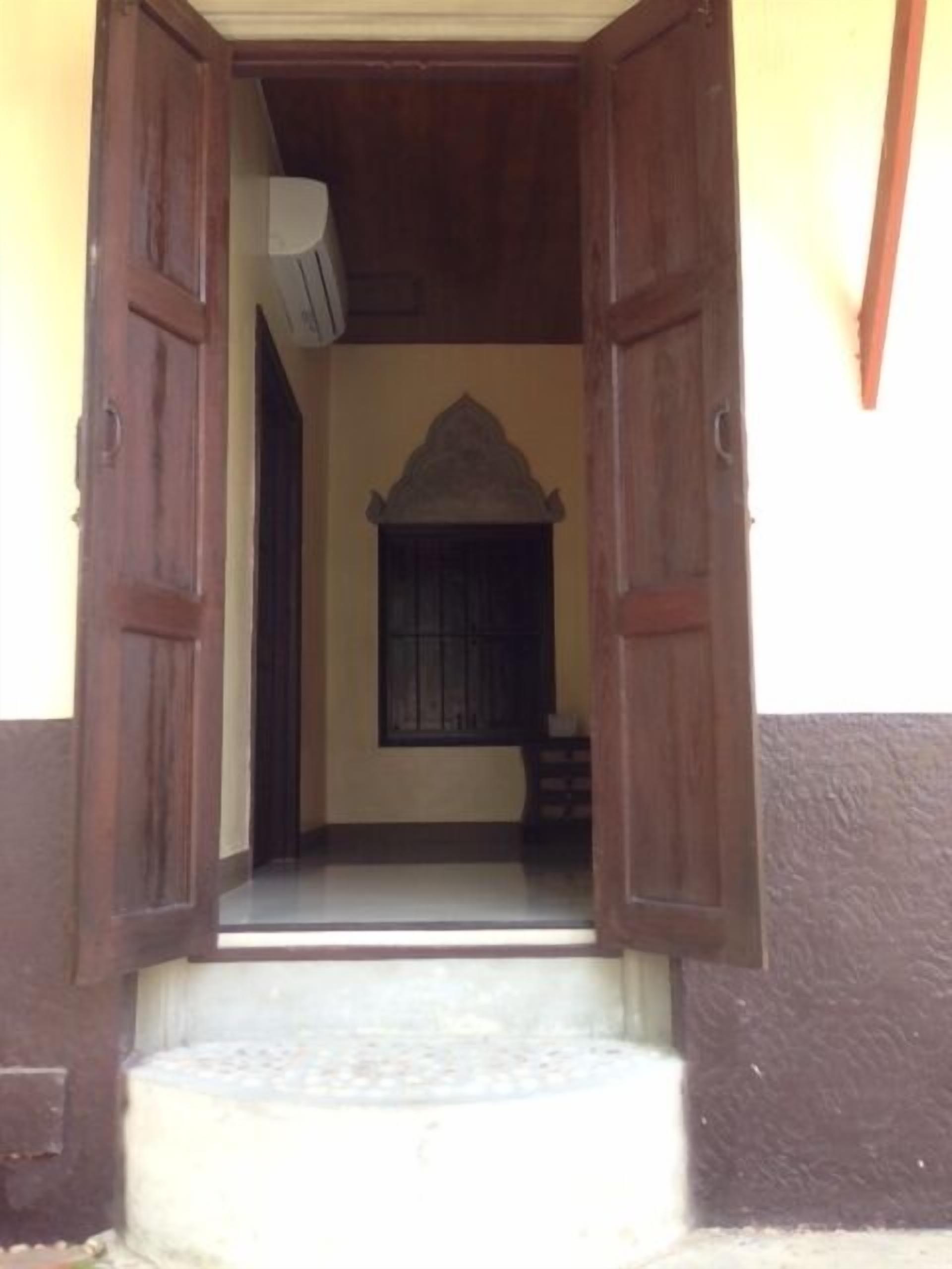 An open doorway leading to a room with a window and a small step.