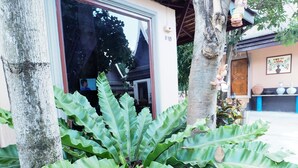 A building with a large window and a potted plant in front. - Sweet Inn Resort Hotel (Bang Pahan)