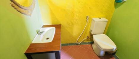 A bathroom with a wooden vanity, a white toilet, and a yellow textured wall.