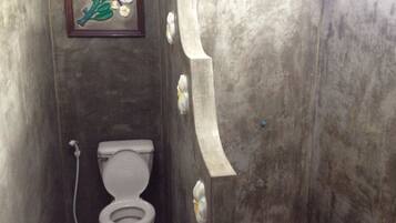 A narrow bathroom with a toilet and a framed picture on the wall.