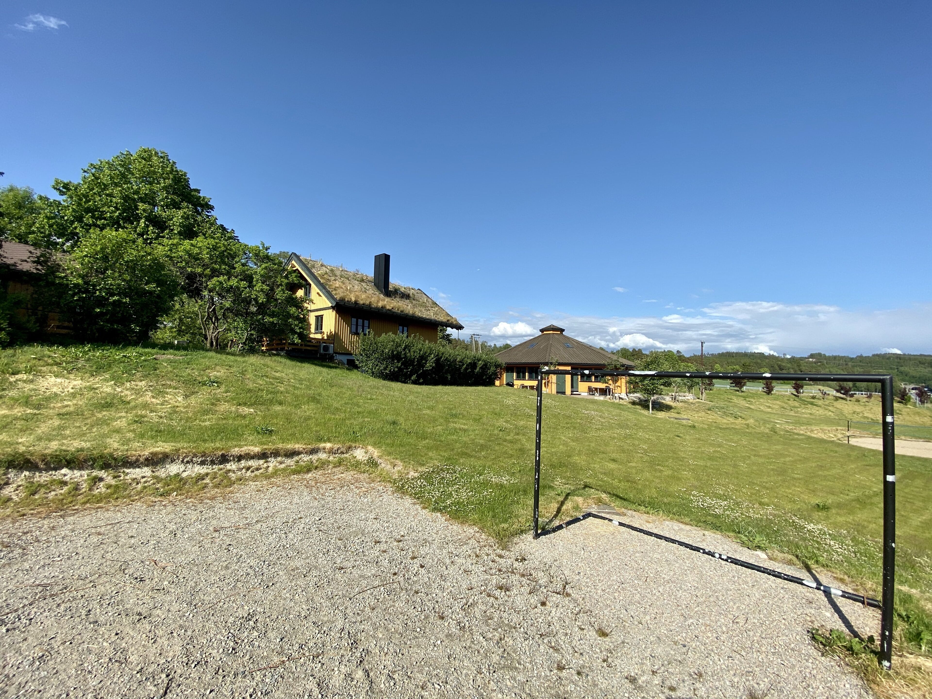 A rustic house with a thatched roof, surrounded by a grassy area and a gravel path.