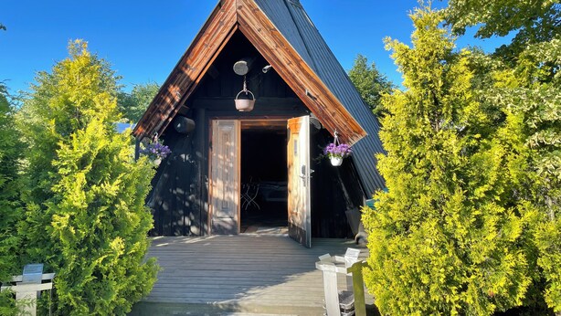 Un chalet rustique avec un toit en pente, un revêtement extérieur en bois et une véranda menant à l’entrée.