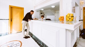 A reception area with a white reception desk, a wooden door, and a marble floor. - Basic Hotel Doña Manuela (Seville)
