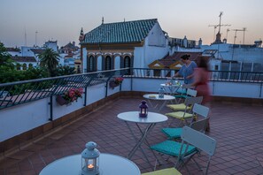 A rooftop terrace with tables and chairs, a lantern, and a view of the cityscape. - Basic Hotel Doña Manuela (Seville)