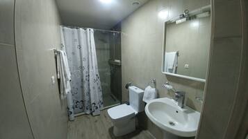 Un baño con inodoro, lavamanos y cabina de ducha de vidrio.