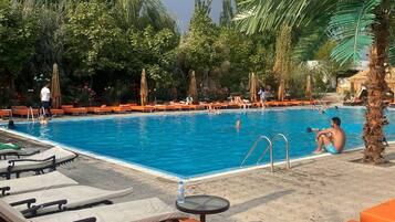 A pool area with lounge chairs and a swimming pool surrounded by greenery.