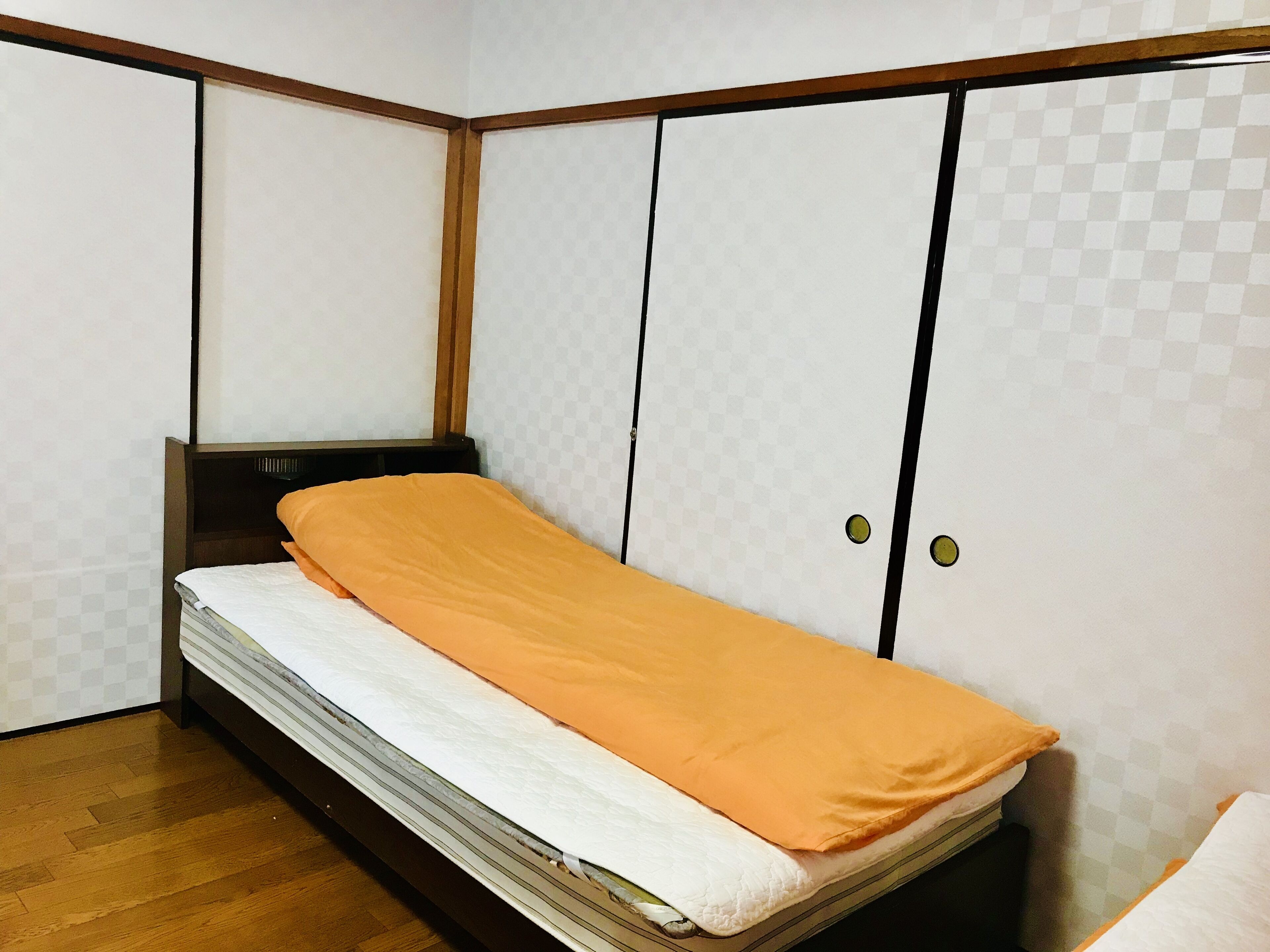 Una habitación pequeña con cama, armario y piso de madera.