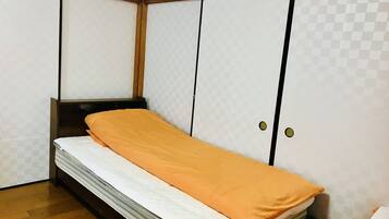 Una habitación pequeña con cama, armario y piso de madera.