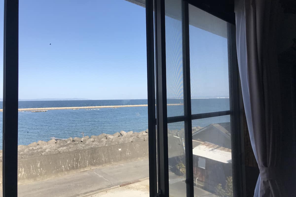 Une vue à travers une fenêtre, avec un ciel dégagé et une étendue d’eau.