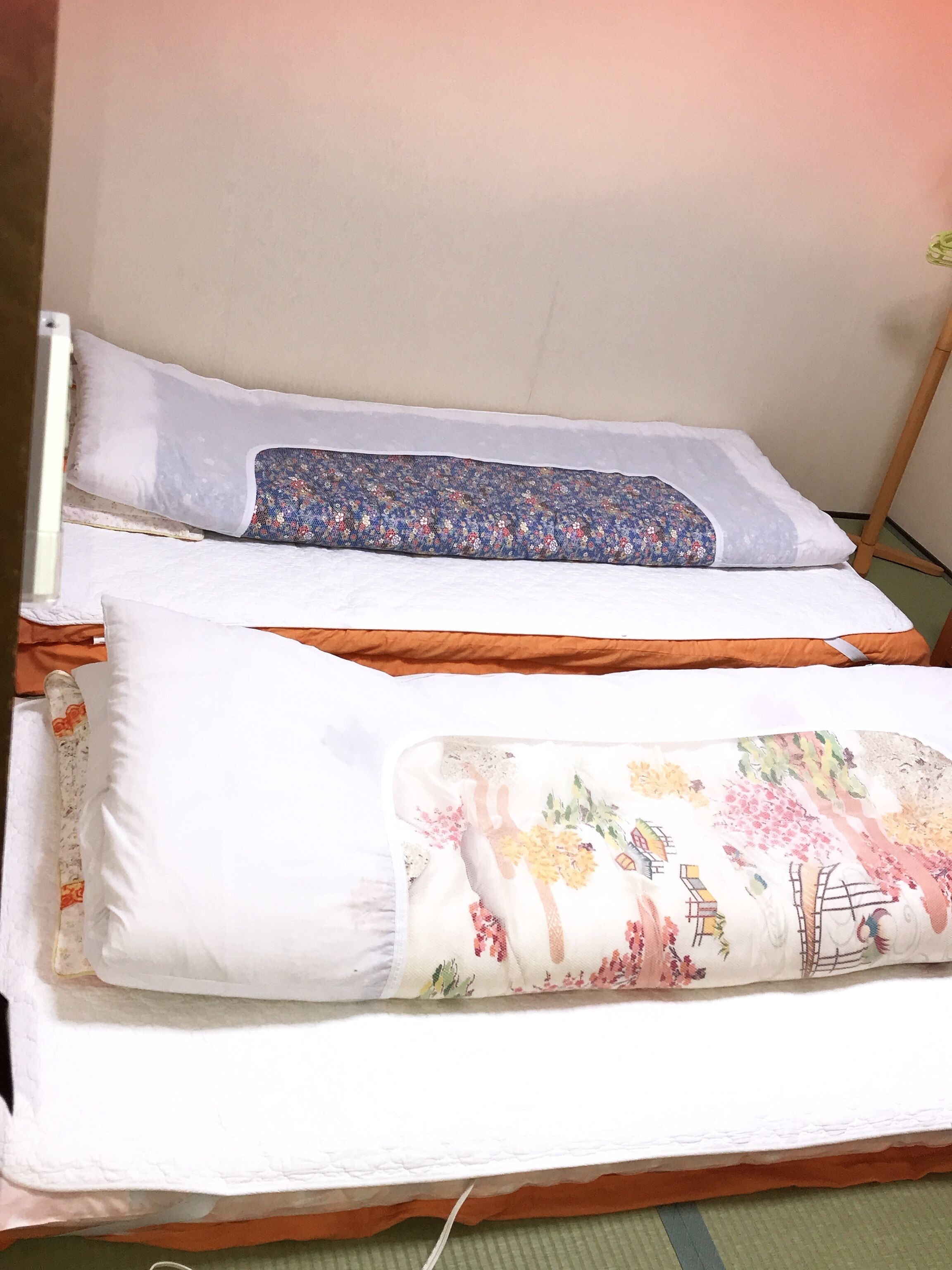 A bed with two pillows, one with a floral pattern and the other plain.