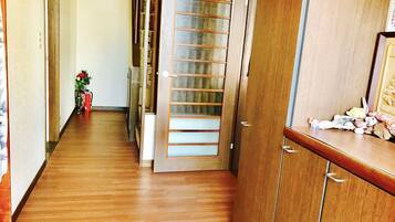 Enter a serene hallway with a door leading to a cozy space, featuring a small plant and a cabinet with a mirror.