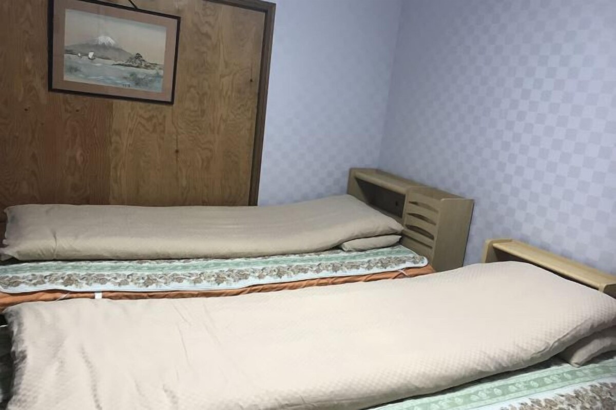 A room with two beds, wooden headboards, and a framed picture on the wall.