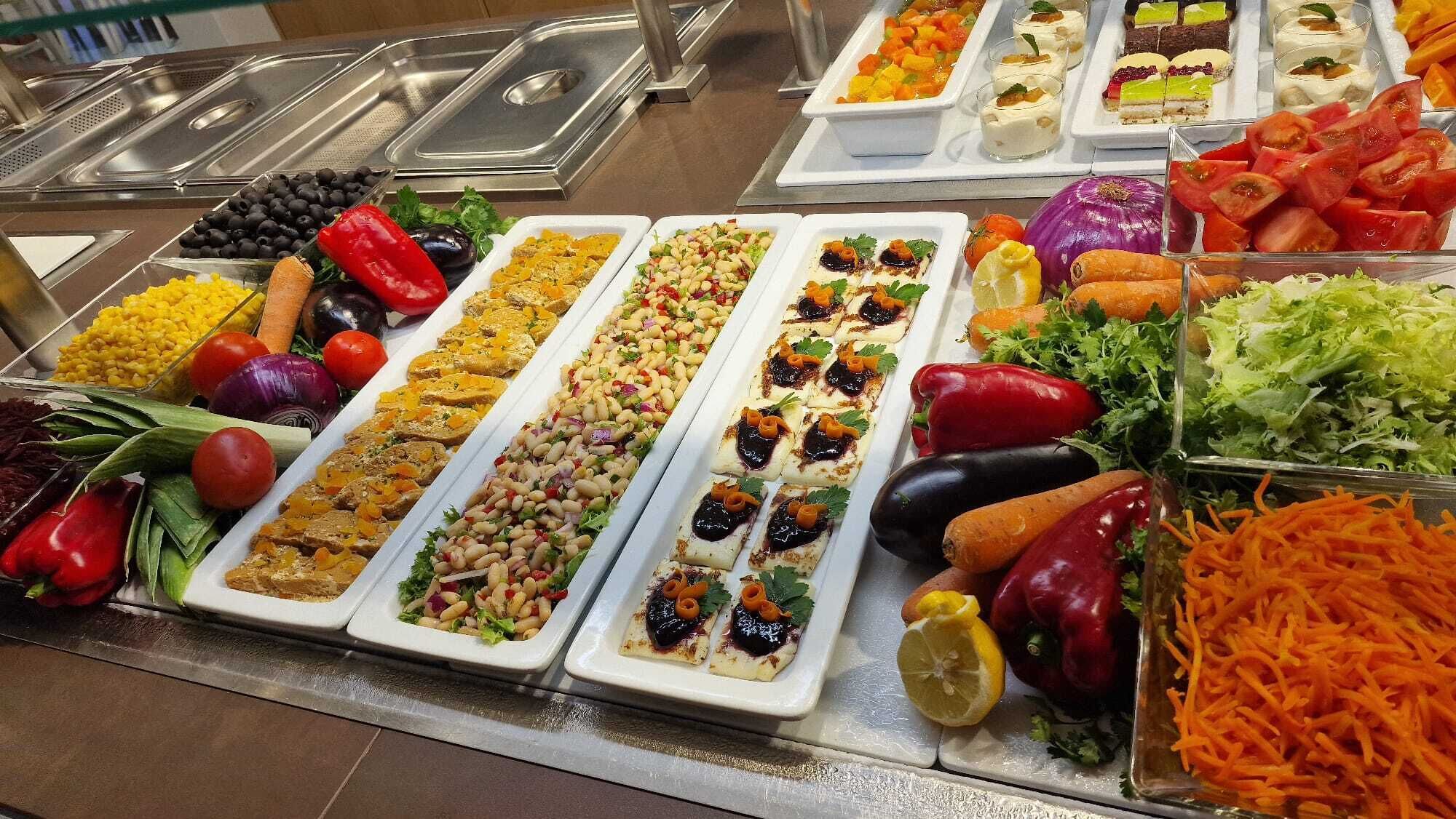 Un buffet proposant une variété de plats, notamment des salades, des légumes et des desserts.