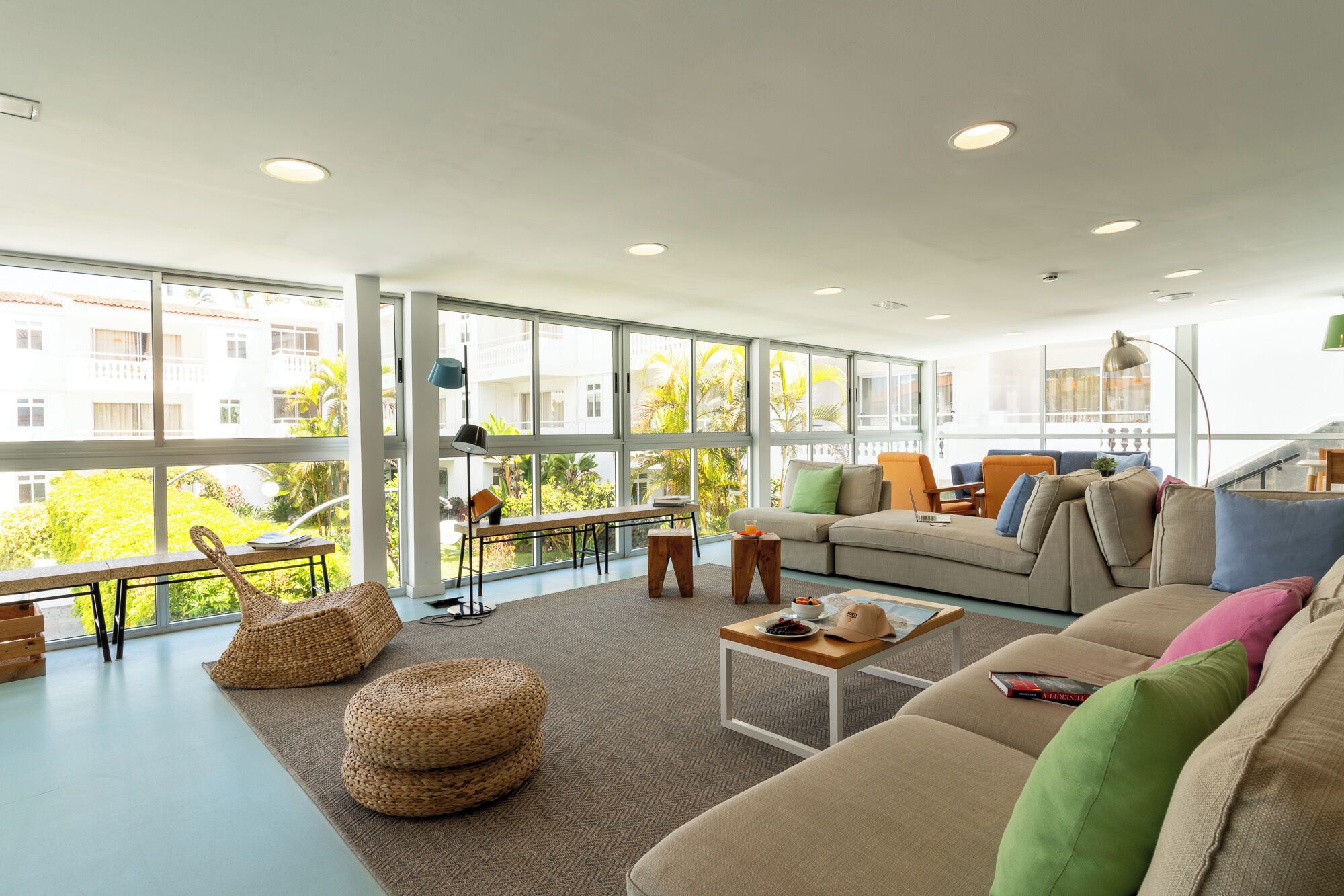 Amplia sala de estar con ventanas grandes, un sofá, una mesa de centro y vistas al exterior.