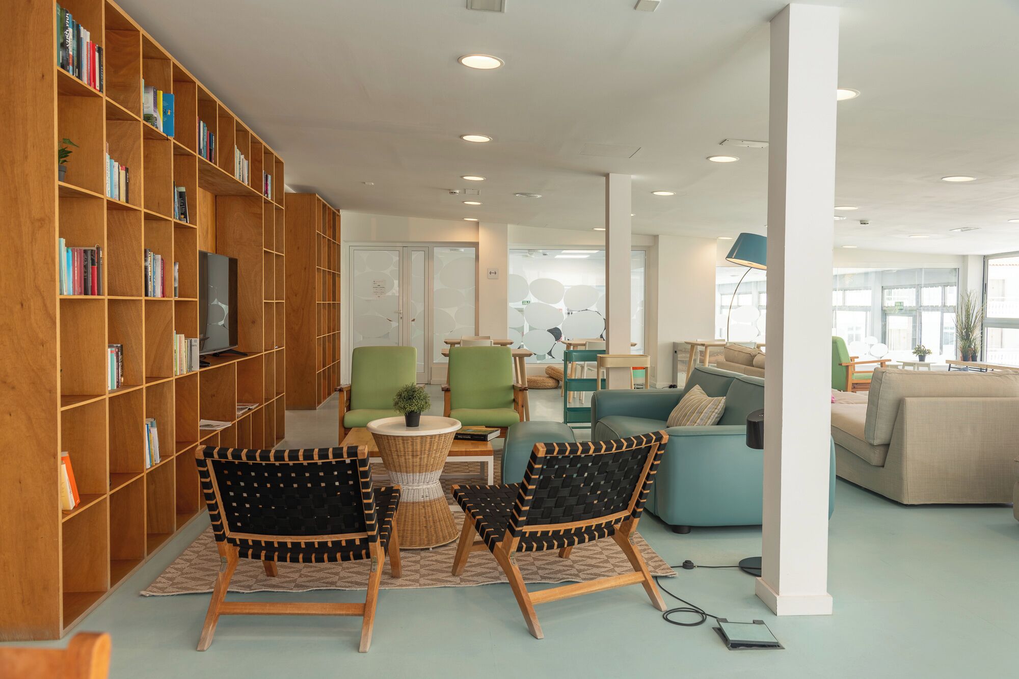 A modern library with wooden bookshelves, comfortable seating, and a bright interior.