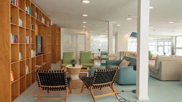 A modern library with wooden bookshelves, comfortable seating, and a bright interior.