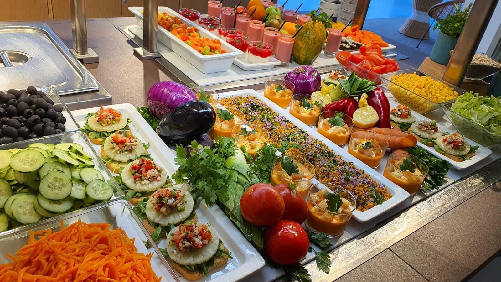 Buffetpöydässä on tarjolla monenlaista ruokaa, kuten vihanneksia, hedelmiä ja salaatteja.