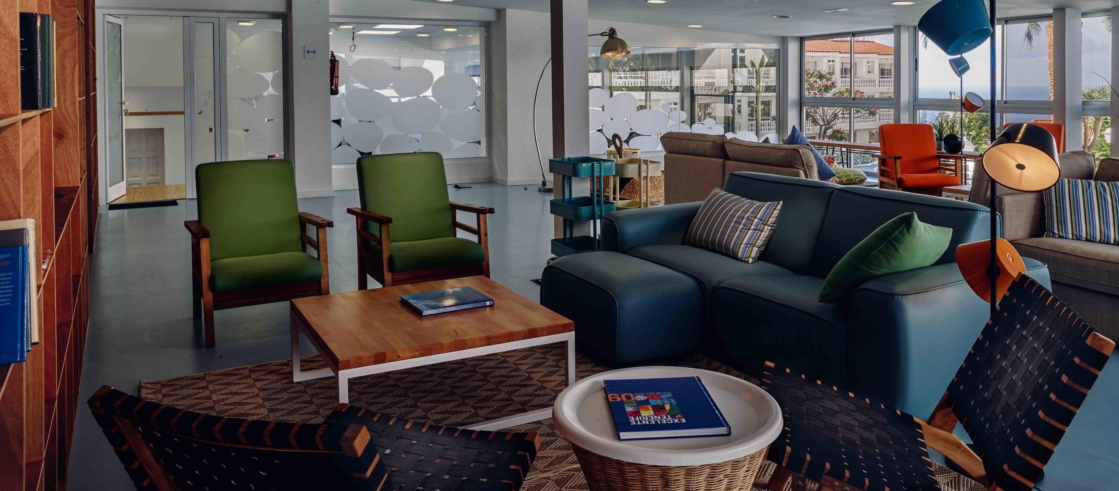 A modern living room with a blue sofa, green armchairs, and a wooden coffee table.