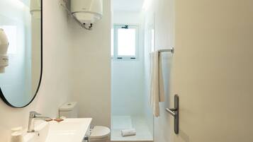 Un baño moderno con lavamanos, inodoro y ducha blancos.