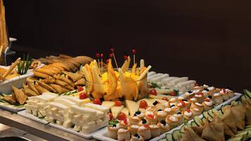 A buffet with various food items including cheese, fruits, and pastries.