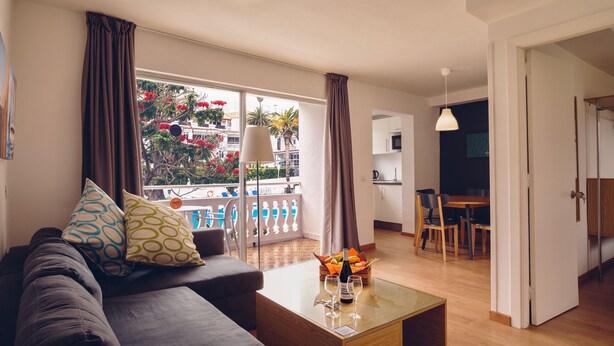 A modern living room with a sofa, coffee table, and a balcony with curtains. - Route Active Hotel (Los Realejos)