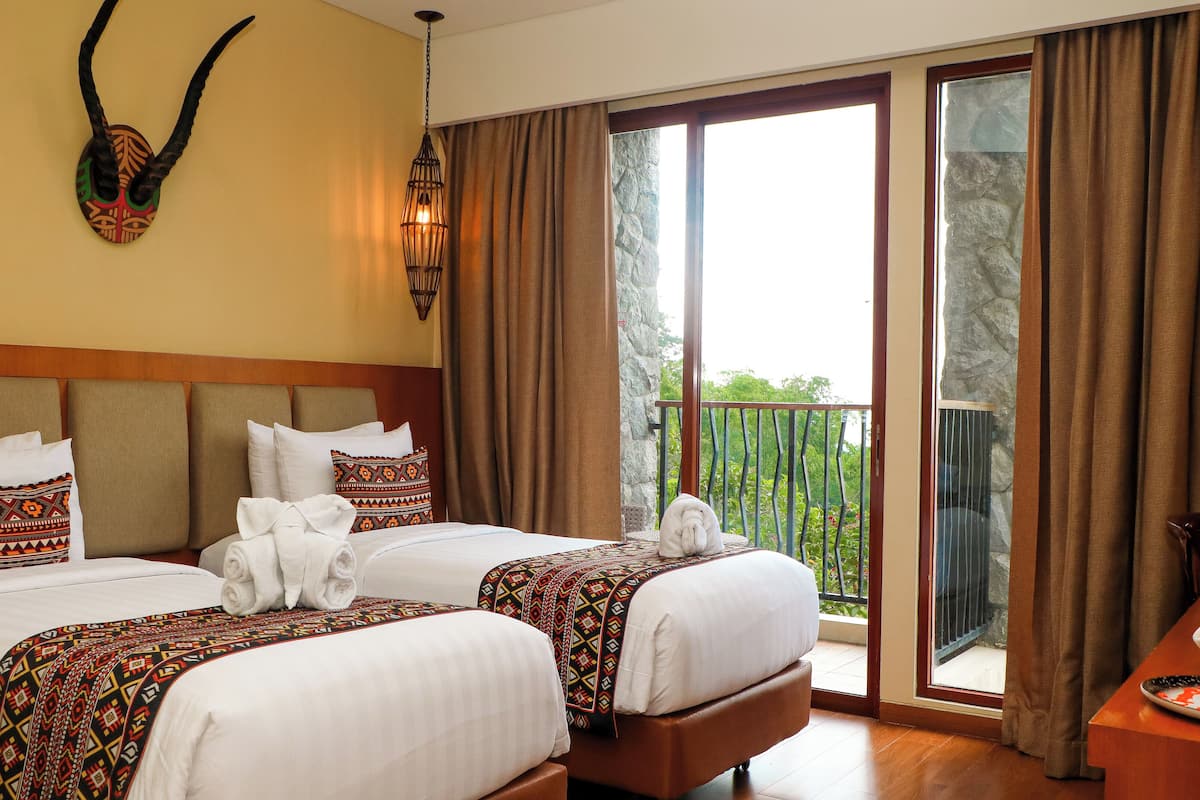 Habitación de hotel con dos camas, un balcón y una mesa de desayuno con fruta.