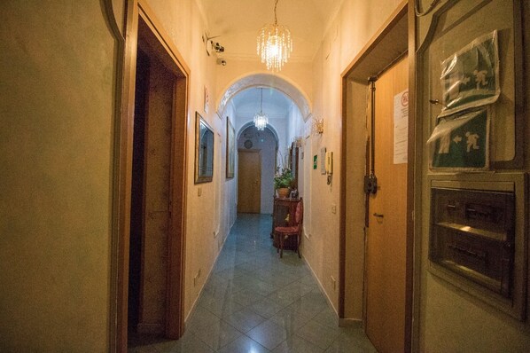 A hallway with a chandelier, framed pictures, and a door with a sign.
