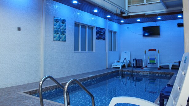 An indoor swimming pool with a tiled floor, a metal pool ladder, and a ceiling with recessed lighting. - Avital Suites And Resort (Lagos)