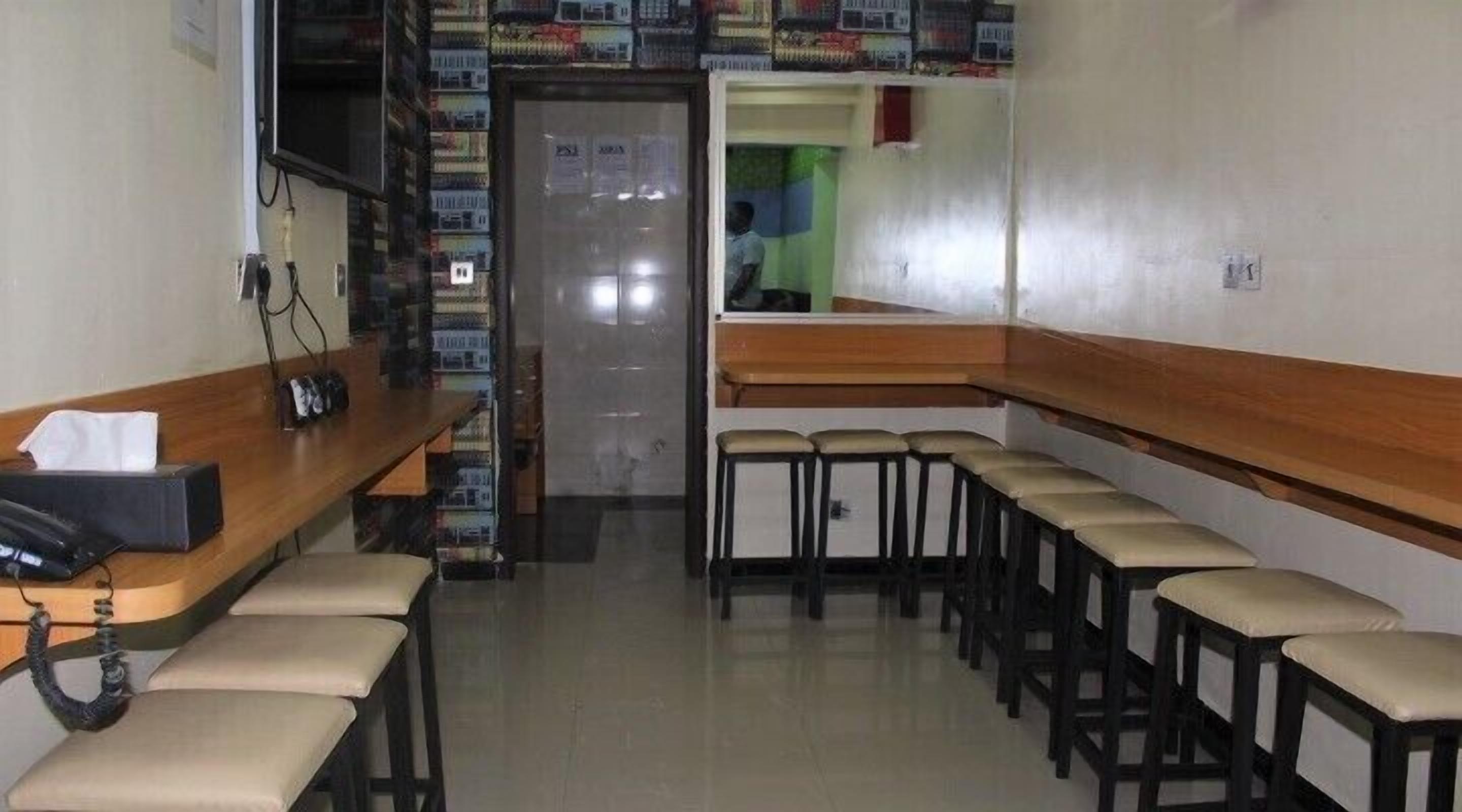 A hotel lobby with a reception desk, a row of bar stools, and a wall of bookshelves.