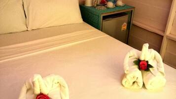 Guests can enjoy a restful night's sleep in this inviting room, featuring a neatly made bed with two plush towels and a single pillow.