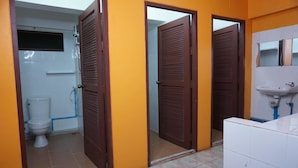 A bathroom with a toilet, a sink, and three doors. - Culture Club Backpackers - Hostel (Ko Pha-ngan)