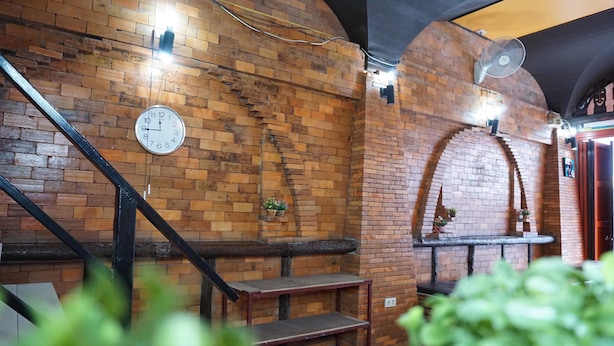 A brick-walled interior with a clock, a staircase, and a fan. - Culture Club Backpackers - Hostel (Ko Pha-ngan)