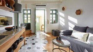 Una sala de estar moderna con un sofá, una mesa de centro y una cocina con un estante de madera y un cuenco.