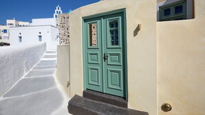 Un edificio con puerta verde, paredes blancas y cielo azul claro.
