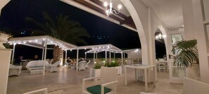 An outdoor patio area with white furniture and string lights. - La Locanda della Castellana (Peschici)