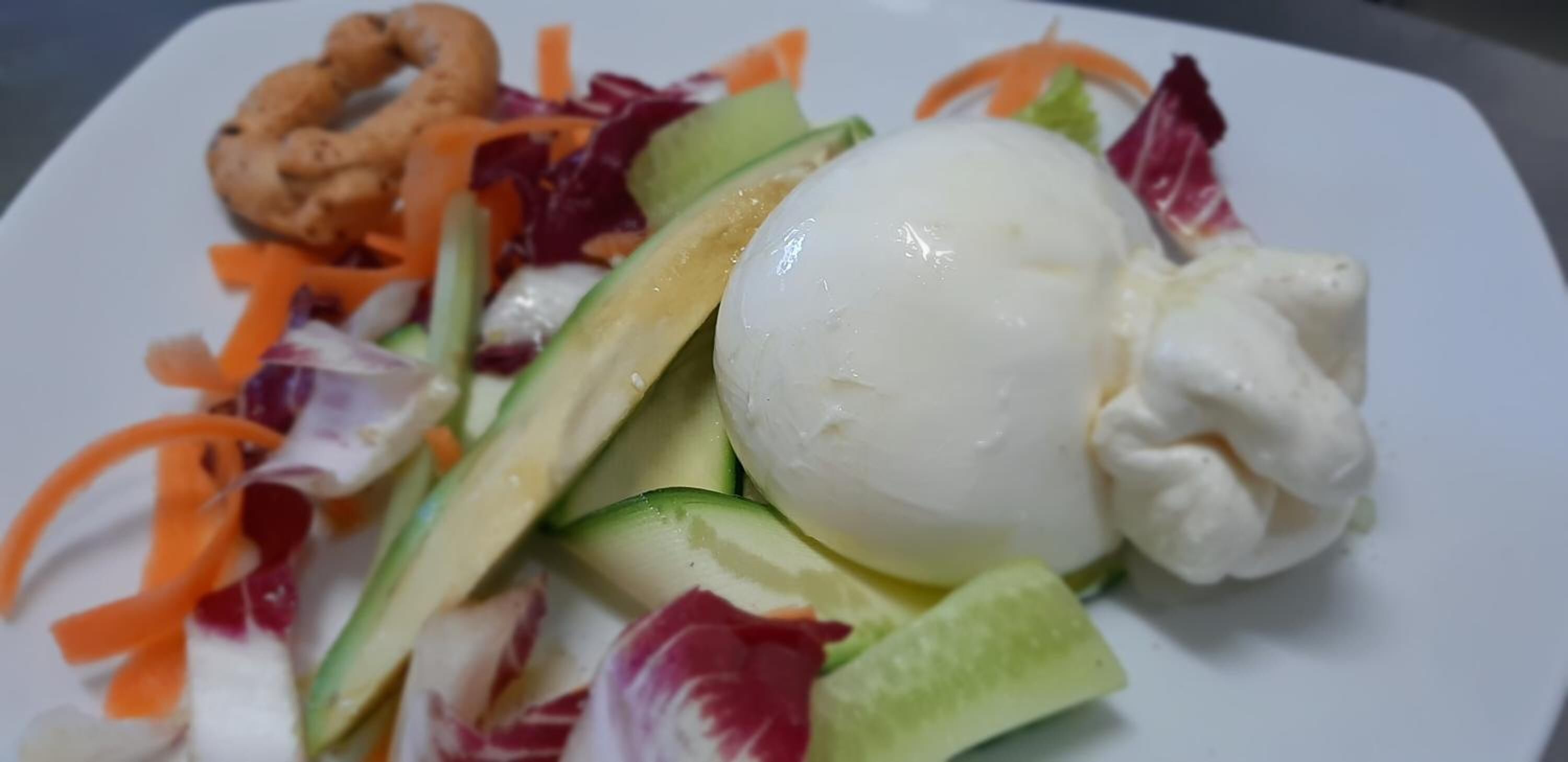 Un piatto con insalata, un uovo sodo e anelli di cipolla.
