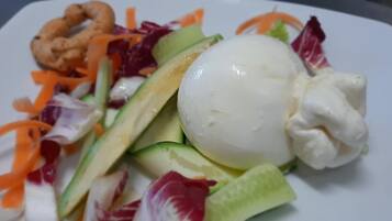 Un piatto con insalata, un uovo sodo e anelli di cipolla.