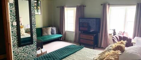 Quarto com cama, televisão, sofá e janela.