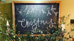 A fireplace decorated with greenery and gold ribbons, with a sign above that reads "Merry Christmas."