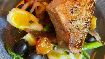 A plate with grilled fish, vegetables, and a lemon wedge.