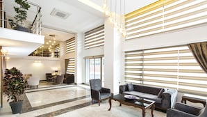 A spacious lobby with a high ceiling, a staircase, and a seating area with a sofa and armchairs. - Perla Arya Hotel (Izmir)