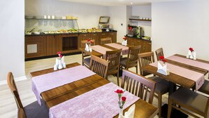 A dining area with wooden tables and chairs, a buffet counter with various food items, and a coffee machine. - Perla Arya Hotel (Izmir)