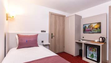 Een hotelkamer met een bed, bureau, koelkast en televisie.