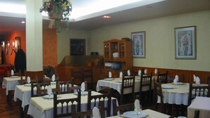 A restaurant with multiple tables set for dining, wooden chairs, and a hanging floral arrangement.