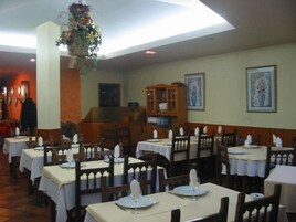 Un restaurante con varias mesas dispuestas para comer, sillas de madera y una decoración floral colgante.