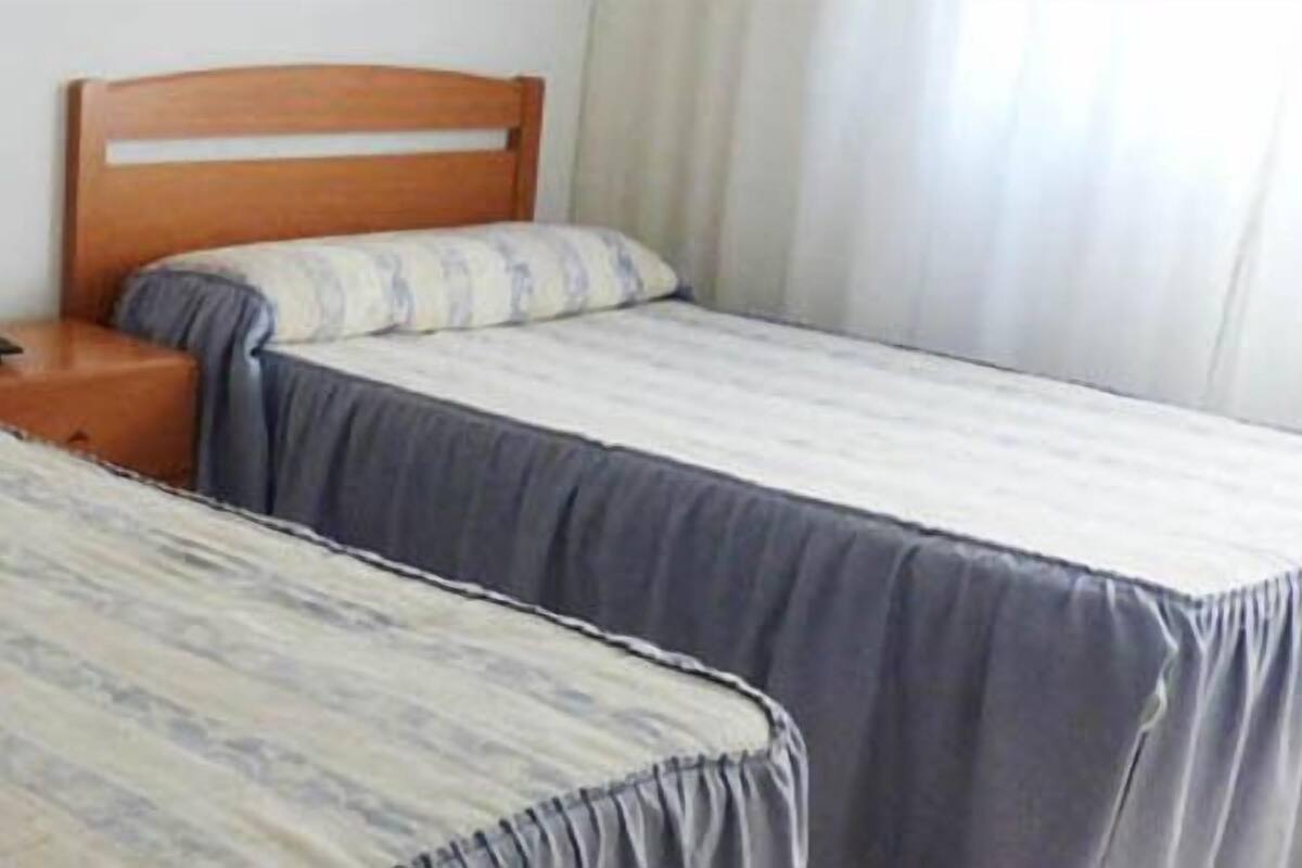 Two single beds with wooden headboards, a bedside table, and a nightstand.