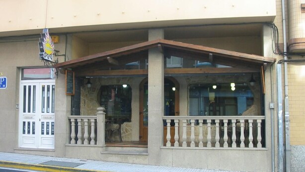 A building with a covered entrance, a white door, and a balcony with a railing.