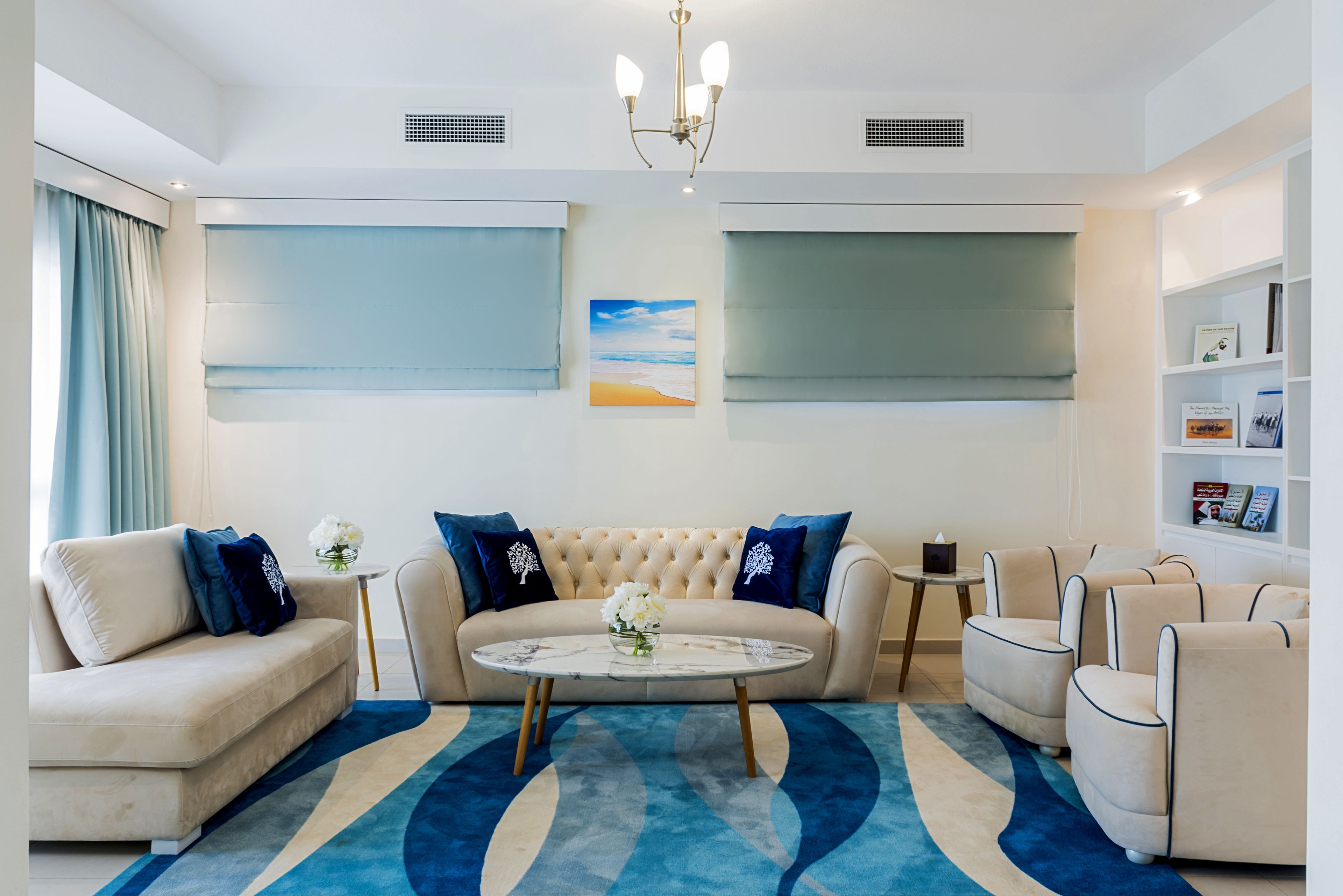 A modern living room with a beige sofa, a round coffee table, and a blue patterned rug.